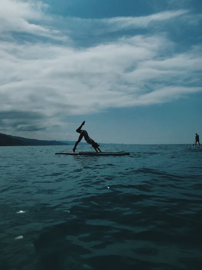 Person practicing yoga on a paddleboard in the Black Sea near Sochi, Russia. Outdoor fitness scene.